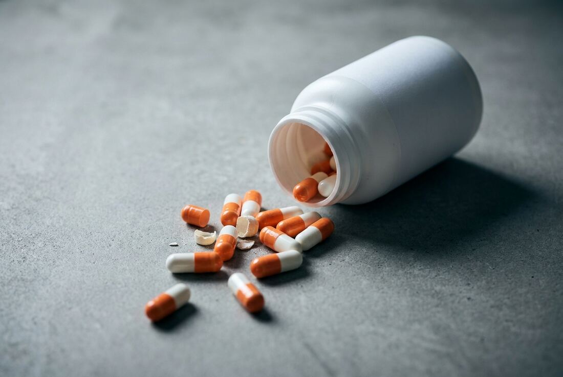 Unlabeled supplement bottle tipped over with capsules spilled out